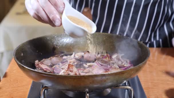 Close-up van chef-kok koken geflambeerd stijl schotel met plakjes lever op een hete koekenpan in restaurant. hand in de handschoen wordt rietsuiker toegevoegd aan het gerecht in de koekenpan. Slow motion. — Stockvideo