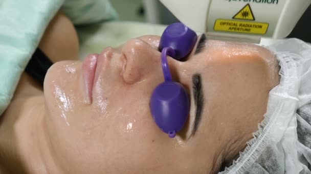 Hautpflege. Frau mit Brille auf Augen bekommt Foto-Verjüngungskur in einem Schönheitssalon. Kosmetikerin, die Gesichtsbehandlung durchführt. Schuss in 4k — Stockvideo