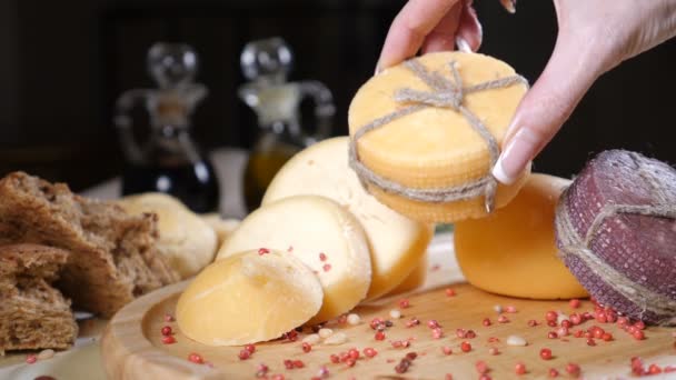 Restaurantkonzept. Final-Touch-Konzept. ein Stück Käse mit Seil dekoriert ist auf Holzgrund mit hausgemachtem Brot, Nüssen und Olivenflaschen. weibliche Hand legt eine andere. Zeitlupe — Stockvideo