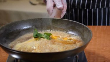 Restoran yemek kavramı. Şef eldiven karamel flambe gözleme pişiriyor. Nane ve limon, limon kabuğu karamel, heyecan pan için ekleyin. Ağır çekim.