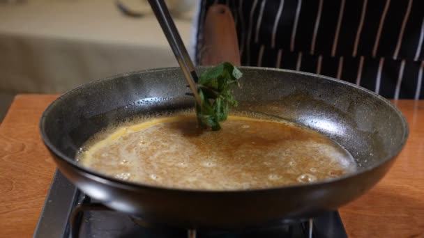 Concepto de cocina del restaurante. Chef en guantes cocina panqueques flamencos en caramelo. Añadir menta y cítricos, cáscara de limón al caramelo, cámara lenta . — Vídeos de Stock