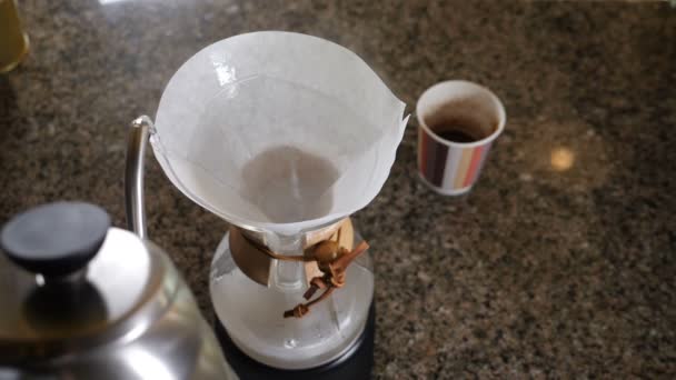 Moderna och alternativa sätt att kaffe. Barista brygger kaffe med kaffebryggare Chemeks. Närbild av händer hälla varmvatten ur pott i pappersfilter med kaffe. Slow motion — Stockvideo