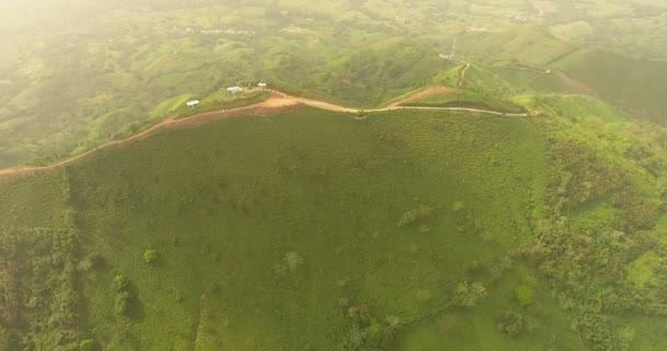Aerial drone birds eye view vídeo on a mountain covered with green grass. No topo da montanha há uma fazenda. Paraíso tropical Ilhas do atol pacífico. Vista superior. Tiros em 4K — Vídeo de Stock