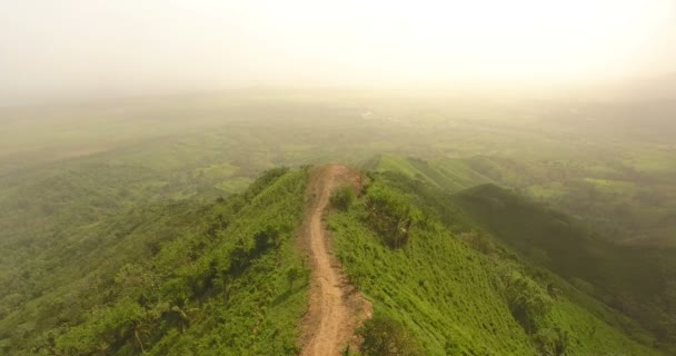 Drohnenvideo aus der Vogelperspektive auf einem mit grünem Gras bedeckten Berg. Auf dem Gipfel des Berges befindet sich ein Bauernhof. tropisches Paradies pazifische Atoll-Inseln. Ansicht von oben. Schuss in 4k — Stockvideo