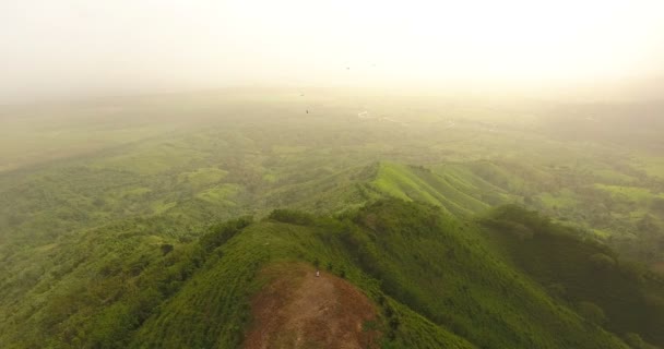 Drohnenvideo aus der Vogelperspektive auf einem schönen Berg, der mit grünem Gras bedeckt ist. Auf dem Gipfel des Berges befindet sich ein Bauernhof. tropisches Paradies pazifische Atoll-Inseln. Ansicht von oben. Schuss in 4k — Stockvideo