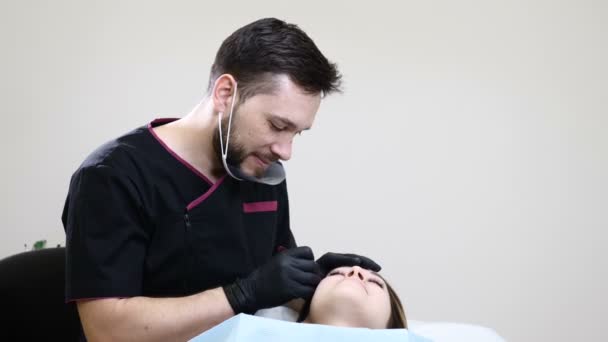 Πορτρέτο της ανδρικής αισθητικός στο μαύρα γάντια κάνοντας διαδικασία μόνιμη μακιγιάζ για γυναίκες eyebrowsusing τατουάζ πένας μηχάνημα. Αισθητικός cosmetologist στο Υπουργικό Συμβούλιο Υγείας Κλινική. — Αρχείο Βίντεο