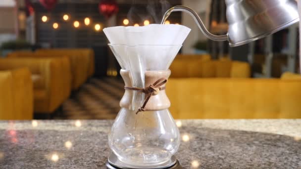 Moderna och alternativa sätt att kaffe. Barista brygger kaffe med Chemex kaffebryggare. Närbild av händer hälla varmvatten ur pott i pappersfilter med kaffe. Slow motion — Stockvideo
