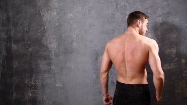 Güçlü ve kas adam vücut geliştiricisi. Adam siyah bir arka plan üzerinde poz kasları yanına bir not yazmak için boş alanı işaret gösterir. güzel Abs ve göğüs kasları.