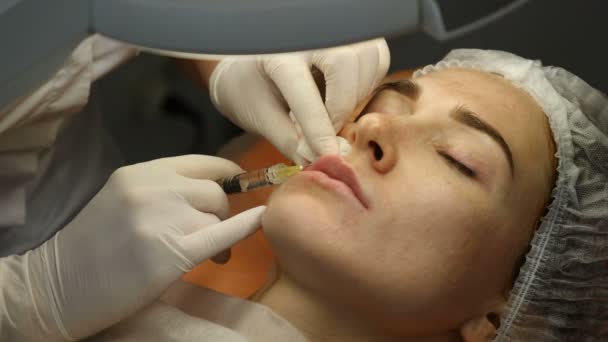 Clínica de beleza. Mãos de esteticista em luvas que fazem a injeção de envelhecimento de cara em uma pele feminina. Uma mulher recebe beleza procedimento de cosmetologia facial. Botox. injecções de colagénio. Tiros em 4K — Vídeo de Stock