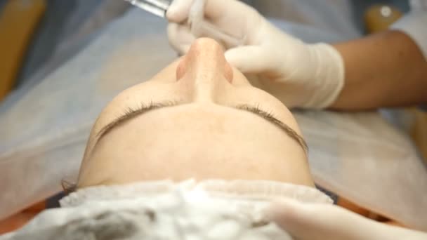 Clinica di bellezza. Estetista mani in guanti facendo l'iniezione di invecchiamento del viso in una pelle femminile. Una donna ottiene la procedura di bellezza cosmetologia facciale. Botox. iniezioni di collagene. Girato in 4k — Video Stock