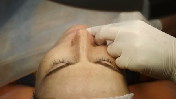 Clínica de belleza Beautician manos en guantes haciendo rostro envejecimiento inyección en una piel femenina. Una mujer obtiene belleza procedimiento de cosmetología facial. Botox. inyecciones de colágeno. Disparo en 4k — Vídeos de Stock