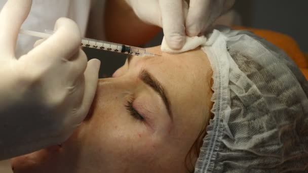 Clínica de belleza Beautician manos en guantes haciendo rostro envejecimiento inyección en una piel femenina. Una mujer obtiene belleza procedimiento de cosmetología facial. Botox. inyecciones de colágeno. Disparo en 4k — Vídeos de Stock