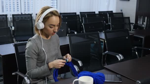 Les gens, la menuiserie, le concept bricolage. Jeune jolie femme en casque tricotant avec aiguille à tricoter et fil bleu. Souris. Mode de vie. Temps passé, Loisirs. Tourné en 4 km — Video