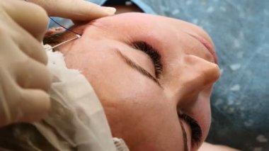 HEALTCARE Kliniği. Genç kadın istemci iş parçacığı yüz yordam kaldırma alır. Şevval Özçelik Güzellik yüz kadın bir anti-aging surat eldiven