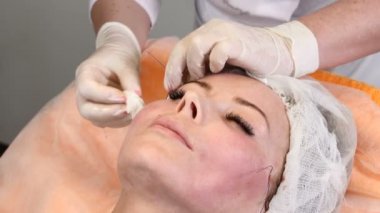 HEALTCARE Kliniği. Genç kadın istemci iş parçacığı yüz yordam kaldırma alır. Şevval Özçelik Güzellik yüz kadın bir anti-aging surat eldiven