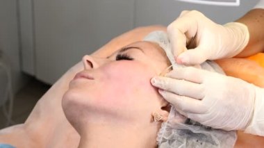 HEALTCARE Kliniği. Genç kadın istemci iş parçacığı yüz yordam kaldırma alır. Şevval Özçelik Güzellik yüz kadın bir anti-aging surat eldiven