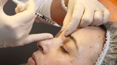 Güzellik Kliniği. Şevval Özçelik Güzellik kadın alnından yüz yaşlanma karşıtı enjeksiyon yapma eldiven eller. Bir kadın Güzellik yüz kozmetik prosedür alır. Botox. kollajen enjeksiyonları