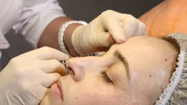 Clinique de beauté. Mains d'esthéticienne dans des gants faisant visage injection anti-âge dans une peau féminine autour des yeux. Une femme obtient la procédure de cosmétologie faciale beauté. Botox. injections de collagène — Video