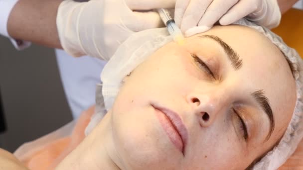 Cosmetician i handskar gör ansiktet lyft injektion till området runt ögonen. Kvinnlig kund blir ansikts skönhet förfarande i sjukvårdsklinik. flytande tråd injektion. Botox. kollagen — Stockvideo