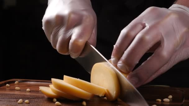 Kock i handskar skivor ost med en kniv. Restaurang. Tabell servering — Stockvideo