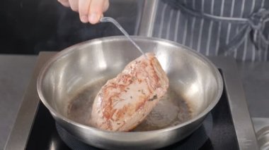 Şef kızarmış ördek göğsü lokantası mutfağı. Maşalar eti çeviriyor. Fransız restoranında klasik Confit Duck pişirme, yakın çekim. Ağır çekim. Yüksek çözünürlüklü çekim.