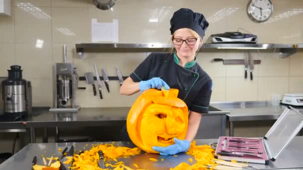 Προετοιμασία για την κατασκευή jack-o-φαναριών την ημέρα του Halloween. Χέρι χαράζει μάτια, μύτη και χαμόγελο με μαχαίρι σε πορτοκαλί κολοκύθα. Κοντινό γύρισμα. 4ια. — Αρχείο Βίντεο