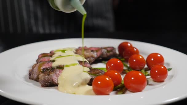 Koken. Lekker eten. Een close-up shot van heerlijk stuk vlees geserveerd samen met kerstomaat wordt gegoten met groene saus. Langzame beweging. Neergeschoten in hd — Stockvideo