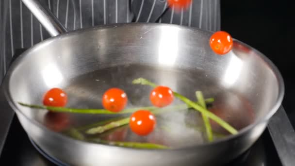Gezond eten en vegetarisch concept. Tomatenkers en asperges vallen in slow motion in hete koekenpan. Dichte stoom stijgt op. Volle kracht geraakt. — Stockvideo