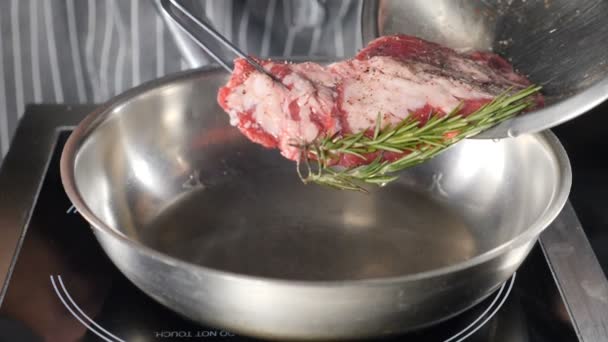 Poner trozo de carne en la sartén. Chef cocinando en la cocina del restaurante. De cerca. Cerca de manos masculinas preparando filete en la sartén. La carne se fríe en la plancha en la cocina. En cámara lenta. Disparo en hd — Vídeos de Stock