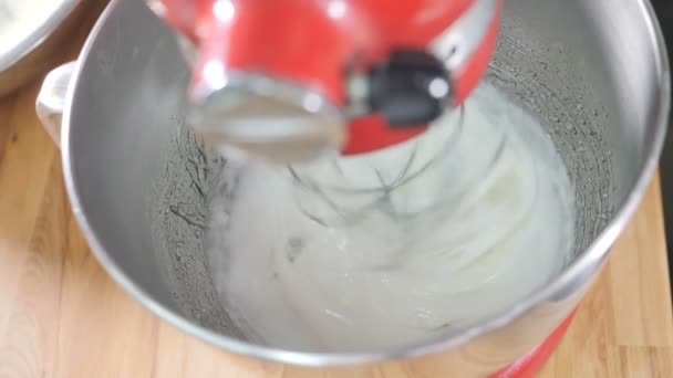 Γλυκό μαγείρεμα. Χτυπώντας τη λευκή κρέμα με ένα μίξερ σε αργή κίνηση. Κοντινό πλάνο του μίξερ βάσης ανάμειξη νόστιμα κρέμα για να κάνει κέικ. Ηλεκτρονικός μείκτης που αναμειγνύει συστατικά σε κρέμα. hd — Αρχείο Βίντεο