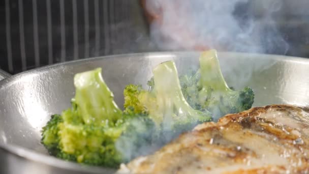 Closeup shot of cooking process in restaurant kitchen. Chef using fire out of gas burner while frying delicious fish on steel frying pan. Slow motion food video. Shot in hd — Stock Video