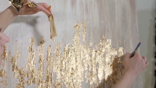 Attractive female artist applying gold leaf to her artwork. Artist decorates picture with tiny sheet of gold. art school, creativity and people concept. Slow motion. Close up. hd — Stock Video