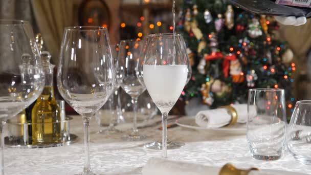 背景にガーランドが点滅し、ぼやけたクリスマスライトとスローモーションでシャンパンを入れてください。クリスマスと新年のお祝い。テーブルの設定、装飾の概念。撃たれた — ストック動画