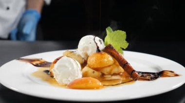 Restoran tarzı yemek servisi. Lezzetli tatlı. Siyah arka plandaki yemek videosunu kapat. Erimiş çikolata döküyorum. Karamel sosunda kızartılmış meyveli dondurma. Lüks restoranda güzel yemekler.