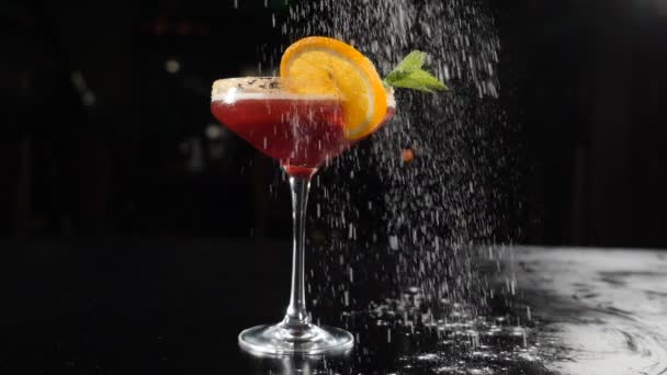 Verse biologische zomerse cocktail op zwarte achtergrond. Wit poeder valt in slow motion. Barman concept. Neergeschoten in hd — Stockvideo