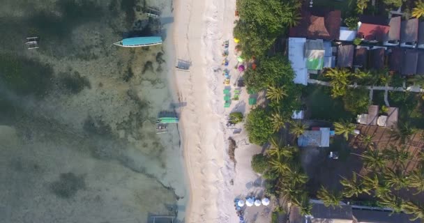Drohnenblick auf die Straße eines balinesischen Dorfes am Meer: Yachten, Palmen, kleine Dächer und Sonnenschirme. von oben nach unten. bali - indonesien. schöne Natur. 4k-Video — Stockvideo