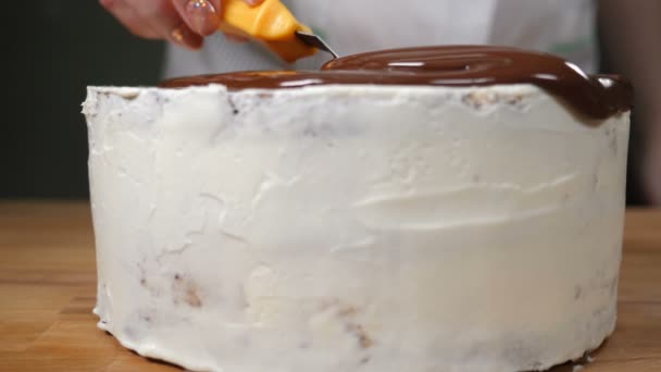 Нарізка шоколадного десерту. Розтоплений шоколад поширюється на смачний торт. Ротовий полив шоколадного торта в білій глазурі, що стоїть на дерев'яній поверхні. Повільний рух. HD відео — стокове відео