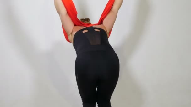 O tânără sportivă atârnă cu susul în jos în studioul de hamac. Fata atractivă exercită yoga antigravitațională în fundal alb. Femeia frumoasă în haine negre practicând intens într-un dispozitiv robust. 4k — Videoclip de stoc