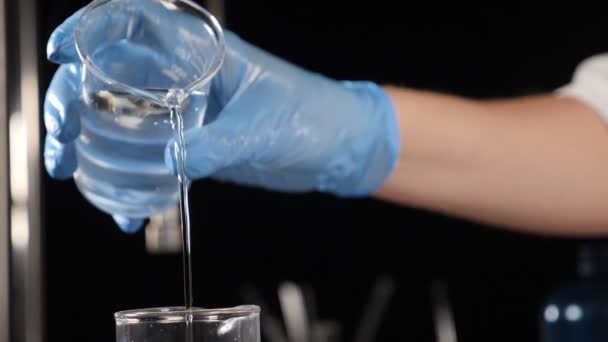 Modern lab concept. Cosmetics manufacture industry. Laboratory assistant mixing ingredients in glass bottle pouring distilled water for body care lotion, cream or shampoo. Slow motion. Full hd — Stock Video