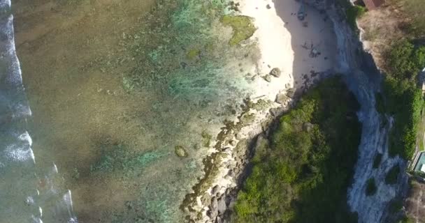 Vista aérea da costa rochosa, oceano panorâmico com ondas salpicantes. Manhã em Bali, Indonésia. Vista drone na praia tropical Bali com praia azul, montanhas rochosas e água do mar límpida do oceano Índico — Vídeo de Stock