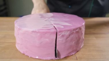 Pastayı ahşap masada iki parçaya bölmek. Keskin bıçağın yakın plan çekimi, pastayı yavaş çekimde kesiyor. Pastanedeki pastacı tatlı servisi yapıyor. Balina Fudgie. Tam Hd