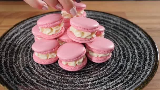 Macaroons - delicious and beautiful french dessert being put on dark plate one on another. Restaurant dessert serving. Slow motion. Full hd — Stock Video