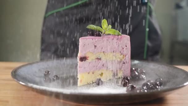 Suikerpoeder wordt gegoten over heerlijk stukje taart prachtig geserveerd met bessen. Slow motion Food kunst. Dessert in coffeeshop concept. Sluit maar af. gebak en bakkerij concept. Vol hd — Stockvideo