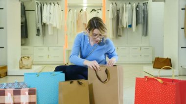 Kara Cuma ve Satış Konsepti. Satış sözcüğü mektup damgası mührü alışverişçi kızın ellerinde. Alışveriş konsepti. Moda butiğindeki çekici bayan müşteri etrafta kağıt torbalarla kameraya gülümsüyor.