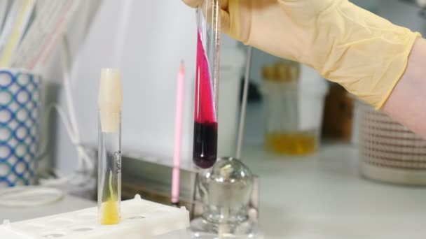 Laboratuvar önlüklü bir araştırmacı eldivenli elleriyle test tüpünü açtı ve laboratuvarda büyüyen bej bakteri kolonilerini izledi. Mikrobik kolonilere odaklan. 4k video — Stok video
