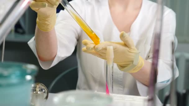 Investigador en laboratorio moderno sostiene en mano abierto tubo de ensayo y observa colonias bacterianas beige creciendo en laboratorio. Concéntrate en las colonias microbianas. Vídeo 4k — Vídeos de Stock