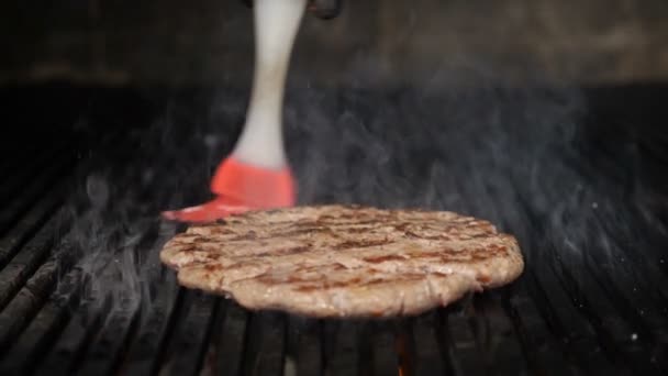 Zeitlupe Food Video mit Feuer. Leckeres Fleisch für Burger auf feurigem Grill gekocht. Feuer brennt und saftige Steaks mit Streifen gekocht werden. Nahaufnahme von Chefkoch leckeren Burger in — Stockvideo