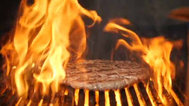 Cocinar la carne para hamburguesa a la parrilla en cámara lenta. Llama subiendo de la rejilla. Hermoso video de comida en cámara lenta. Hamburguesa cocinada en la cocina del restaurante. Full hd — Vídeo de stock