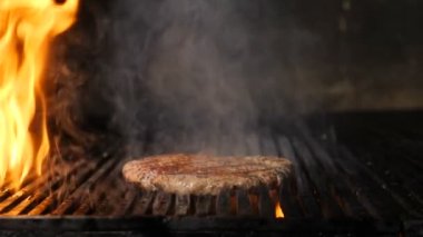 Şef hamburger için ağır çekimde et pişiriyor. Restoranda ızgara hamburger eti. Şefin eli sıcak ızgarada kıyma ve yağlı yağlı hamburger hazırlıyor. Tam Hd