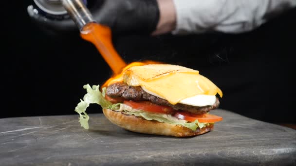 Chef usando maçarico para queimar queijo em hambúrguer saboroso. Cozinhe fatias de derretimento de queijo usando fogo queimando fogão e fazer hambúrguer na cozinha do restaurante. Movimento lento. hd completo — Vídeo de Stock